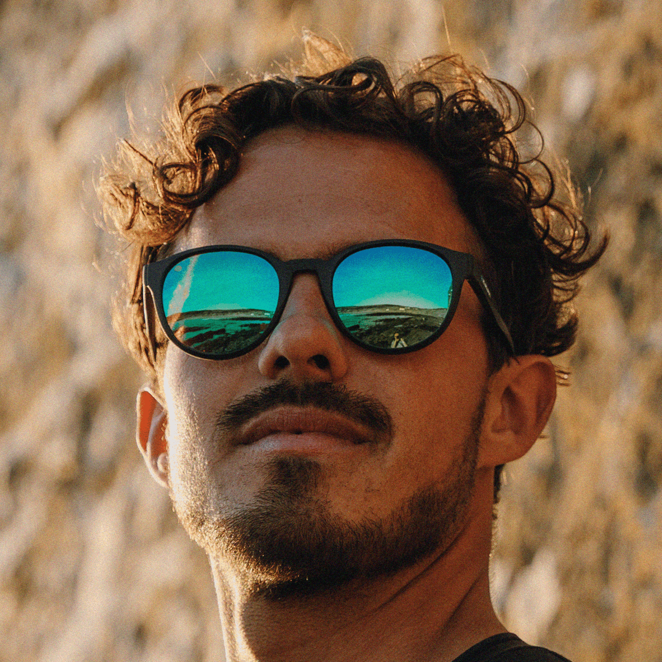 Man wearing Kukuna® Hope Cove lifestyle sunglasses with green mirror lenses, showcasing a stylish outdoor vibe.