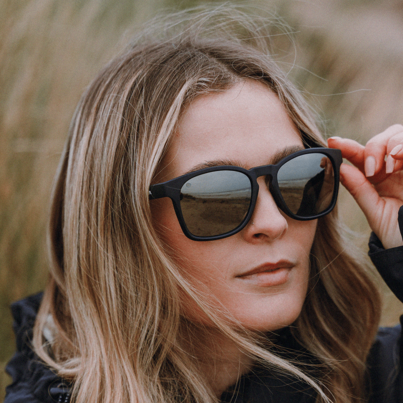 Woman wearing Kukuna® Dawlish durable sports glasses with black frame and polarised grey mirror lens