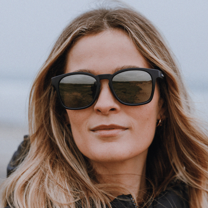 Woman wearing Kukuna® Dawlish adventure sunglasses with black frame and  polarised grey mirror lens 